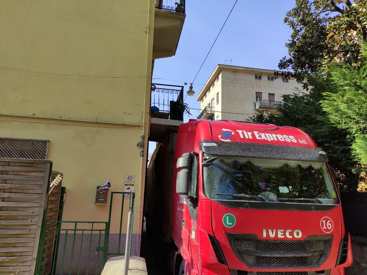Le foto del camion che è rimasto incastrato sotto un balcone bloccando la via